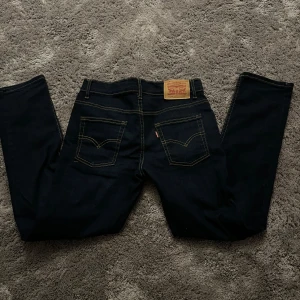 Levi's 512 Slim Nyskick! - Säljer ett par snygga Levi's 512 Slim Taper jeans i mörkblå färg. De har en slim fit och är i storlek 152. Byxorna är i toppskick och ser ut som nya. Fråga på om det är något du undrar!