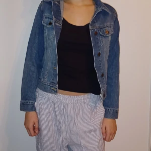 Blå jeansjacka - Säljer en klassisk blå jeansjacka i bra skick. Den har en normal passform med långa ärmar och knappar framtill. Perfekt för vår och sommar, och funkar lika bra till vardags som till fest. Ett måste i garderoben för en avslappnad stil!