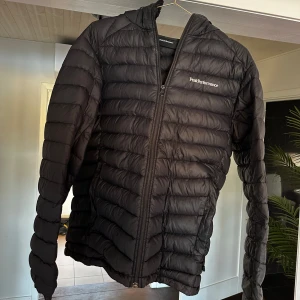Svart pufferjacka från Peak Performance - Säljer en svart pufferjacka från Peak Performance i mycket bra skick. Jackan har en dragkedja framtill och är perfekt för höst och vinter. Den är långärmad och quiltad, vilket gör den både varm och stilren. Perfekt för kyliga dagar! 🖤