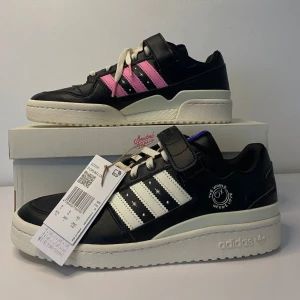 Adidas Forum Low sneakers - Säljer ett par Adidas Forum Low sneakers i svart med vita och rosa detaljer. Skorna har en cool design med snörning och kardborreband för extra stil. Perfekta för både vardag och fest! Helt nya med taggar kvar.