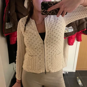 Beige stickad kofta med dragkedja - Säljer en superfin vit stickad kofta i nyskick! med dragkedja framtill. Den har ett snyggt mönster och praktiska fickor. Perfekt för både höst och vår! 🧶