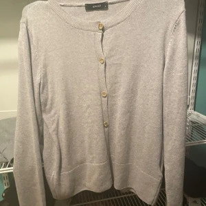 Grå kofta från LCW ECO - Säljer en stilren och bekväm grå kofta från LCW ECO i storlek S. Den har långa ärmar och knäpps med snygga träknappar framtill. Perfekt för både vardag och kontor. Koftan är i mycket bra skick och passar perfekt till höst- och vårgarderoben.