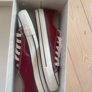 Vinröda sneakers med vita detaljer - Snygga vinröda sneakers från ISL i storlek 39. De har vita snören och en vit sula med svarta ränder. Perfekta för en casual look och passar till både jeans och kjol. Skorna är i nytt skick. Säljer då de ej passar. 
