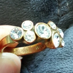 Guldfärgad ring av märket Pilgrim, ställbar  - Säljer en snygg guldfärgad ring med flera stora, glittrande stenar. Ställbar storlek. Perfekt för att ge lite extra bling till din outfit. Ringen har en unik design med stenar i olika storlekar som verkligen fångar ljuset. Passar både till vardags och fest!