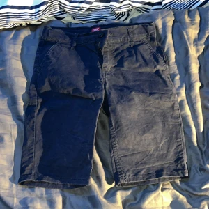 Mörkblå shorts från Levi's - Säljer ett par mörkblå shorts från Levi's i bra skick. De är tillverkade i bomull och har en klassisk design med dragkedja och knapp. Perfekta för sommaren eller våren. Passar bra till både vardag och lite mer avslappnade tillfällen. Chinos shorts 