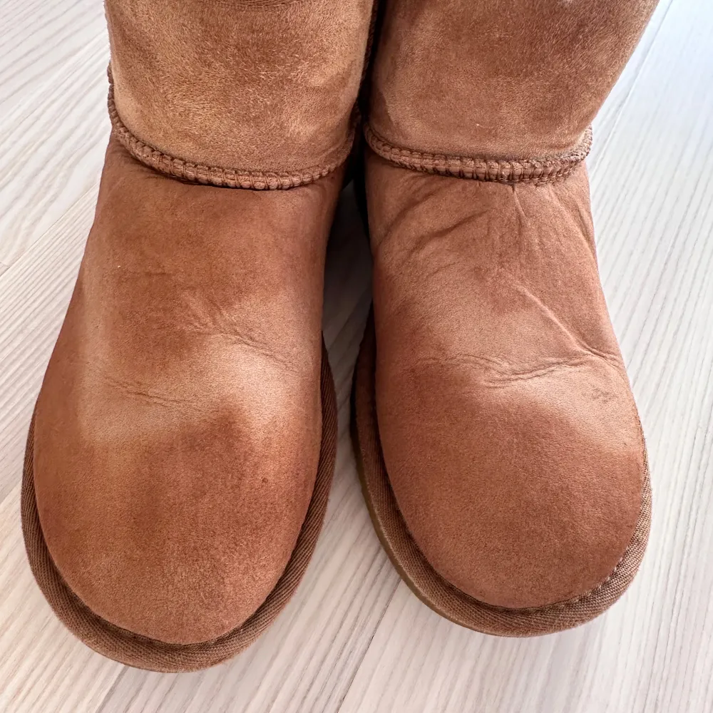 Säljer ett par bruna UGG boots i bra skick. De är fodrade med mjukt fårskinn som håller fötterna varma under kalla dagar. Perfekta för höst och vinter! Inkluderar en flaska UGG Cleaner & Conditioner för att fräscha upp dem och få bort vattenfläckaran, originalmedel. Säljes i befintligt skick.. Skor.