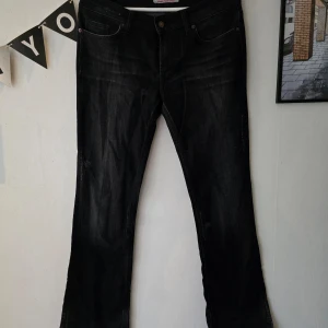 Svarta y2k jeans från Fornarina modell Flirt-bit - Säljer ett par svarta jeans från Fornarina i storlek 32. De är tillverkade i 98% bomull och 2% elastan, vilket ger en skön stretch. Byxorna har en klassisk femficksdesign och en snygg tvättad look. Perfekta för både vardag och fest!