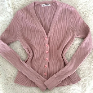 Rosa  kofta. Rosa cardigan. Rosa tröja med knappar - Säljer en superfin rosa kofta från Glamorous i storlek S. Den är ribbad och har en v-ringad design med knappar framtill. Sparsamt använd och inga synliga defekter! 