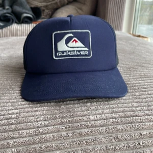 Blå keps från Quiksilver - Säljer en snygg helt ny blå keps från Quiksilver med ett broderat märke på framsidan. Justerbar passform för att sitta bekvämt på huvudet. Skriv vid fler frågor!