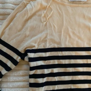 Beige och svart randig tröja från Zara - Säljer en snygg beige och svart randig tröja från Zara. Den har långa ärmar och är perfekt för både vår och höst. Tröjan är i bra skick och passar perfekt för en casual look. Supermjuk och bekväm att ha på sig!