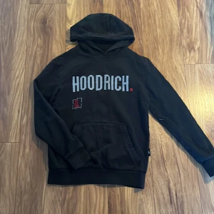 Svart hoodie från Hoodrich - Säljer en svart hoodie från Hoodrich i bra skick. Den har en stor logga på framsidan och en cool design på baksidan. Perfekt för höst och vinter med sin mysiga huva och känguruficka. Passar både till vardags och chillkvällar. 🖤