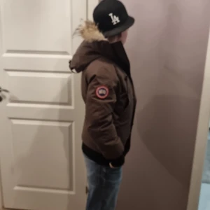 Mörk brun Canada gosse jacka - Säljer min Canada gosse jacka eftersom jag hade tänkt att skaffa en ny. Jackan ör varm och skön och sitter perfekt för xs och små s användare.  Jackan är cirka 3 år gammal men bara används under detta år. Pälsen är äkta och är från en prärievarg, dock är pälsen lite trasig på sidan då lite lim ramlat av men det är därför jag säljer för bra pris. Såklart är hela jackan äkta  men har fått den från min farbror som present. Fråga och köp!!!