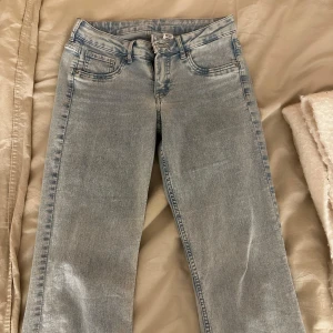 Lågmidjade Bootcut jeans i ljusblå denim - Säljer ett par snygga bootcut jeans i ljusblå denim från HM De är lågmidjade och har en klassisk femficksdesign. Perfekta för en avslappnad stil och passar till både vardag och fest. Skicket är bra och de är superbekväma att ha på sig!