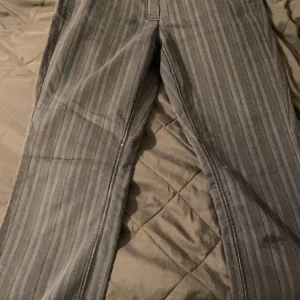 Randiga byxor från Steilmann - Säljer ett par snygga randiga byxor från Steilmann. De är grå med tunna vita ränder och har coola detaljer som färgglada sömmar vid fickorna. Perfekta för både vardag och fest! 🖤