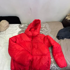 Röd pufferjacka - Säljer en snygg röd pufferjacka som är perfekt för kalla dagar. Jackan har en dragkedja framtill och en mysig huva. Den är i bra skick och passar perfekt för vintern. Perfekt för att hålla värmen och se stilren ut samtidigt! 🔥