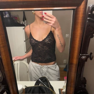 Svart spetslinne - Säljer ett snyggt svart spetslinne med tunna axelband. Perfekt för en utekväll eller fest. Linnet är i bra skick och har en vacker blommig spetsdesign som ger en elegant touch. 🌺