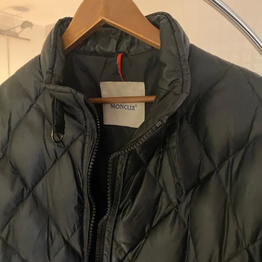 Säljer en snygg svart quiltad dunjacka från Moncler. Jackan har en dragkedja framtill och är perfekt för kyliga dagar. Den är i mycket bra skick och har långa ärmar. Passar perfekt för höst och vinter. Perfekt för dig som vill hålla stilen i kylan! 🖤4 motsvarar storlek M-L. Jackor.