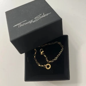 Guldarmband från Thomas Sabo - Säljer ett elegant guldarmband från Thomas Sabo. Armbandet har en fin kedja med en rund hängande detalj. Perfekt för både vardag och festliga tillfällen. Passar perfekt med berlocker 