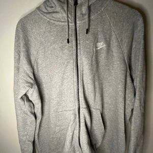 Nike zip - Grå zip hoodie från Nike. Denna har använts mycke och är lite smått sliten men skulle ändå säga att den är i bra skick. Tror att detta är herr storlek men funkar på tjejer också!