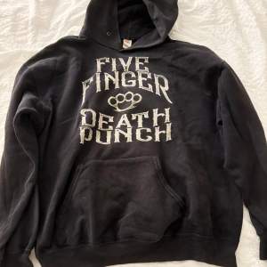 Säljer en svart hoodie med stort tryck av Five Finger Death Punch på både fram- och baksidan. Den har en klassisk känguruficka och en bekväm huva. Den är storlek L men skulle ger säga att den är M. Mycket skön hoddie som knappt är använd