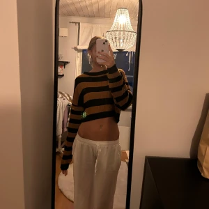 Randig croppad stickad tröja - Säljer en superfin randig croppad tröja i svart och orange. Den är stickad och har långa ärmar, perfekt för höst och vår. Tröjan är i bra skick och passar perfekt för en avslappnad stil. 🧡🖤