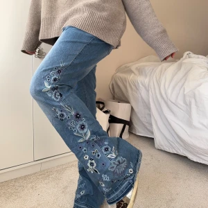Bootcut jeans - Sååå coola jeans med blommiga detaljer!! De är 41xm över midjan och 77cm i innerbenet🩵🩵