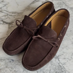 Bruna Marzio City Loafers - Snygga bruna loafers i mocka med klassisk design från Marzio. Skorna kostar nya 2250 Skorna har en dekorativ snörning framtill och en bekväm passform. Perfekta för en stilren look.