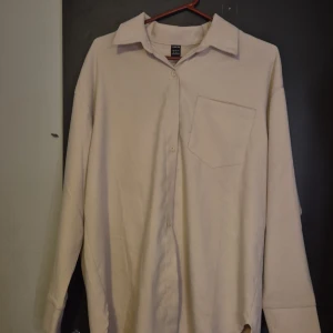 Beige långärmad skjorta från Shein - Säljer en stilren beige långärmad skjorta från Shein. Skjortan har en klassisk krage och en bröstficka. Perfekt för en minimalistisk look.