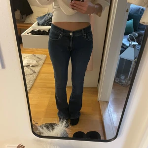 Blå bootcut jeans - Snygga blå bootcut jeans med låg midja. Perfekta för en avslappnad stil. Klassisk design med fem fickor och knappgylf. Omsydda till mer low Waits men inget som syns🥰midjemått - 31cm men är stretchiga. Innetbenslängd - 80