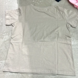 Beige t-shirt - Säljer en stilren beige t-shirt i mjukt material. Perfekt för en avslappnad look. T-shirten har korta ärmar och en klassisk rund halsringning.