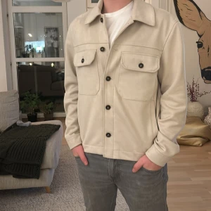 Beige jacka från Zara - Säljer en stilren beige jacka från Zara med knappar framtill och två bröstfickor. Jackan har en klassisk krage och långa ärmar, perfekt för en avslappnad look.