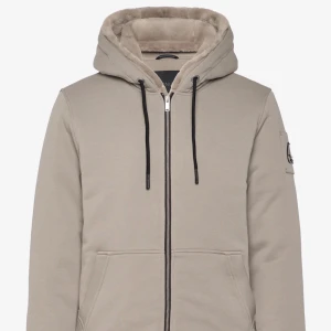 Beige moose knuckles tröja - Snygg beige tröja med huva och dragkedja framtill. Tröjan har en mjuk, pälsliknande foder på insidan och svarta dragsnören. Perfekt för kyligare dagar. Och vår dagar. Jag köpte tröjan för 4699kr på Boozt mitt pris är 3500kr kvitto finns kvar och tröjan ligger kvar i originalförpackningen, kan bara mötas upp. Tveka inte att skriva vid intresse