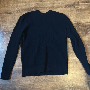 Svart ribbad tröja från Zara - Säljer en stilren svart ribbad tröja från Zara. Tröjan har långa ärmar och en klassisk rund halsringning. Perfekt för en minimalistisk look.