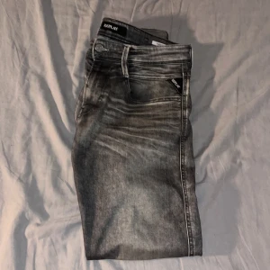 Grå jeans från Replay - Snygga grå jeans från Replay med en cool tvättad look, fråga för bild p defekt. De har en klassisk femficksdesign och en knappgylf. Perfekta för en avslappnad stil.