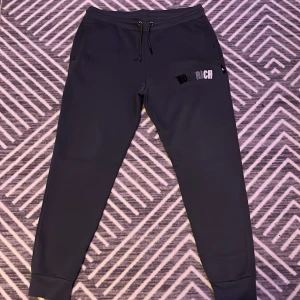 Svarta mjukisbyxor från Hoodrich - Snygga svarta mjukisbyxor från Hoodrich med justerbar dragsko i midjan. Byxorna har en stilren design med logotypdetalj på benet och bekväma muddar vid bensluten. Perfekta för en avslappnad stil.