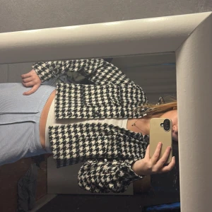 Svartvit rutig jacka - Säljer en snygg svartvit rutig jacka med knappar framtill. Jackan är croppad och har långa ärmar, perfekt för en trendig look. Den är i en stilren design som passar till många olika outfits.