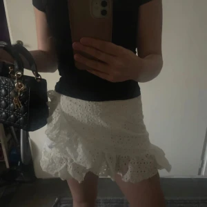 Vit kjol med volangdetaljer - Söt vit kortkjol med volangdetaljer och broderat mönster. Perfekt för sommaren och våren💕