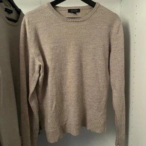 Beige merinoulltröja från Paul & friends - Säljer en stilren beige tröja från Paul & friends i 100% merinoull. Tröjan har långa ärmar och ribbade muddar vid ärmslut och nederkant. Perfekt för kyligare dagar med sina förstärkta armbågar.