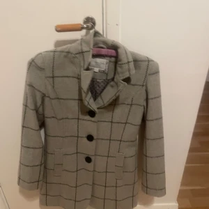 Grå rutig kappa  - En grå snygg kappa med svarta ränder och svarta prickar inuti