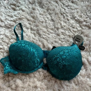 Turkos spets-bh 80B - Säljer en vacker turkos bh med spetsdetaljer. Den har justerbara axelband och en elegant design som ger ett lyxigt intryck. Perfekt för att känna sig extra fin. Helt ny
