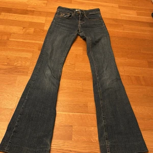 Blå bootcut jeans från Lois - Snygga blå bootcut jeans från Lois med klassisk femficksdesign. Tillverkade i Spanien, dessa jeans har en stilren look med Lois-logga på bakfickan. Perfekta för en avslappnad stil.