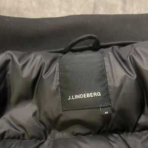 J.lindberg jacka  - Säljer denna feta j-lindberg jacka i nyskick, märke på ärmen, varmt fyllt dun, size m, true to size, grabb på bild är 180 63 kg.