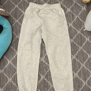 Grå mjukisbyxor från H&M Divided - Säljer ett par grå mjukisbyxor från H&M Divided. Byxorna har en elastisk midja med snörning och är tillverkade i en mjuk bomullsblandning. Perfekta för en avslappnad stil.