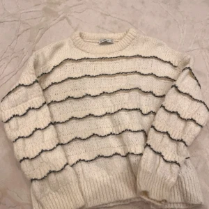 Zara vit stickad tröja  - Säljer en mysig vit stickad tröja från Zara med svarta vågiga ränder. Tröjan har långa ärmar och en rund halsringning. Säljs inte längre på Zara