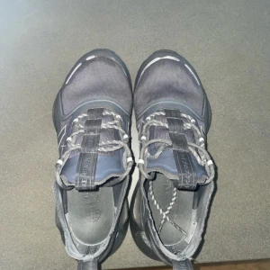 Grå sneakers från Adidas - Snygga grå sneakers från Adidas med en modern design och bekväm passform. Skorna har snörning och en stilren look som passar perfekt för vardagsbruk. Tillverkade i syntetmaterial för hållbarhet och komfort. Skick 6-7 av 10. Köpta för 1100kr. Har riktigt stiliga reflexer. Och säljs för 699kr priset kan diskuteras. Tveka ej vid minsta funderingar 