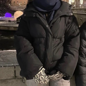 Svart pufferjacka - Säljer en svart pufferjacka som är perfekt för kalla vinterdagar. Jackan har en normal passform och långa ärmar, vilket gör den både varm och bekväm. Den är i mycket bra skick och passar perfekt för vinterns alla äventyr. Dragkedja framtill för enkel stängning.     Nypris var 600, den är i väl omhändertagen och i bra skick