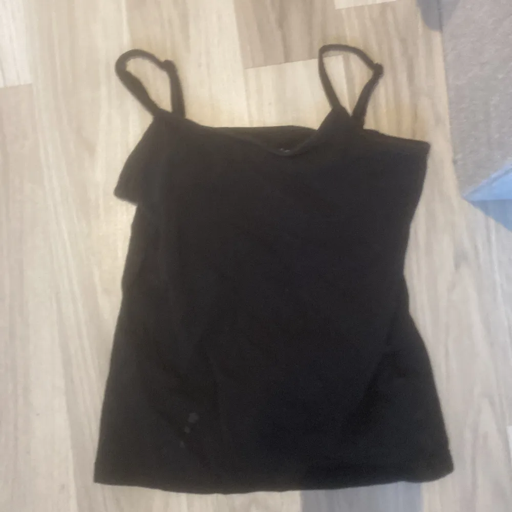 Säljer ett svart linne från Basic You i ekologisk bomull. Perfekt för sommardagar eller som ett basplagg i garderoben. Linnet har smala axelband och är i bra skick med en liten fläck på framsidan. Passar både till vardags och festliga tillfällen.!!PRIS KAN DISKUTERAS !!. Yläosat.