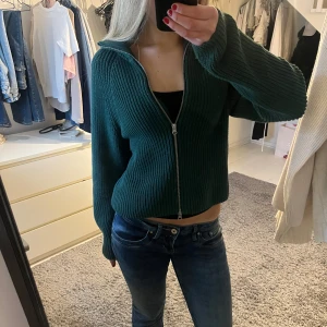 Mörkgrön stickad kofta med dragkedja - Säljer en supermysig mörkgrön stickad kofta med dragkedja framtill. Perfekt för höst och vinter! Den har långa ärmar och en skön passform som är lite loose. Perfekt att ha över en t-shirt eller linne.💚💚