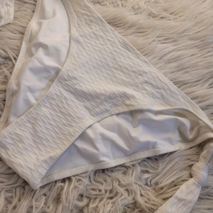 Vit bikiniunderdel med knyt - Säljer en superfin vit bikiniunderdel i ribbat material. Den har knytbara sidor för perfekt passform och en stilren look. Perfekt för sommarens alla stranddagar! 🏖️