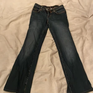 Blå bootcut jeans - Säljer ett par snygga blå bootcut jeans i bra skick. De har en klassisk femficksdesign med orange sömmar och en bekväm passform. Perfekta för både vardag och fest! 🕺Relativt korta i benen, passar någon under 167cm och neråt i längdmässigt 